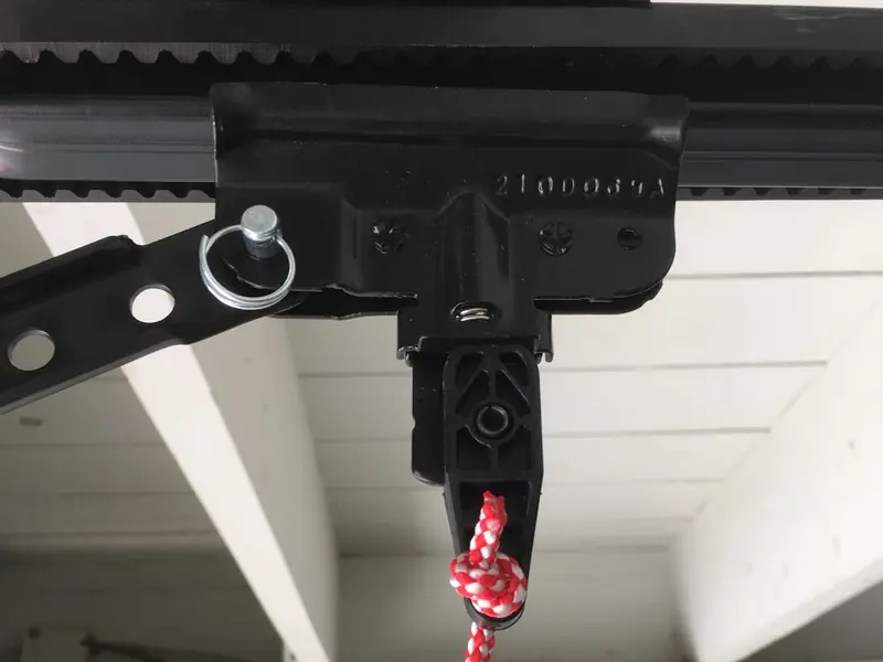 Close-up of an opener trolley on its rail with the red and white emergency release cord hanging down